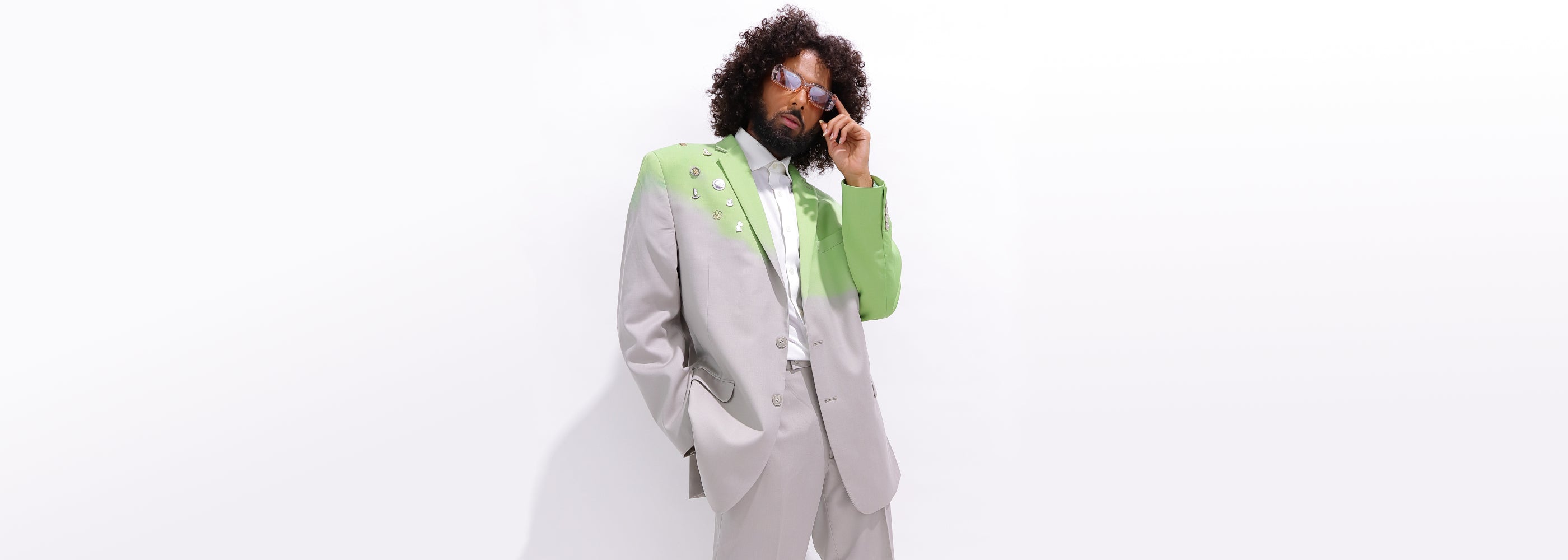 curly hair man wear dip dyed designer lime green and tan blazer with enamel pins